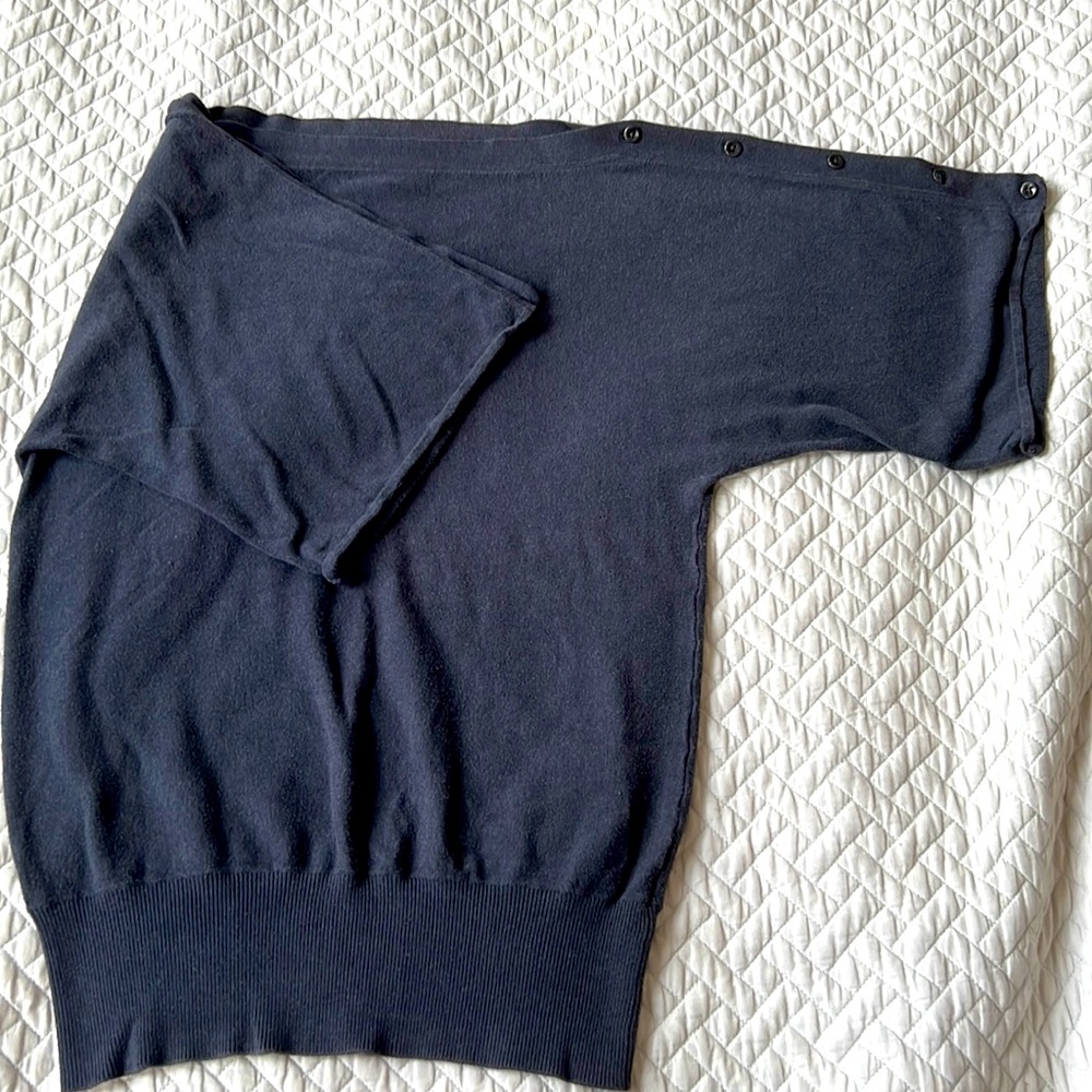Fashionable grey jersey shirt with boatneck and buttons along dolman sleeves.